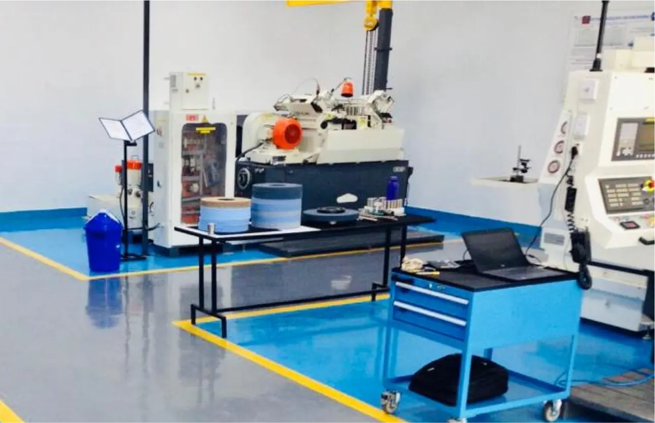 Blue epoxy floor with yellow safety markings in a machine workshop